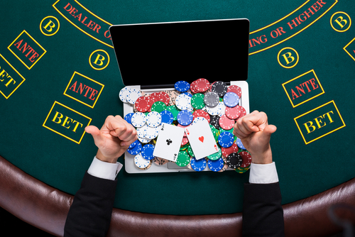 joueur de casino dont l'ordinateur est posé sur une table de jeu et couvert de jetons et de cartes
