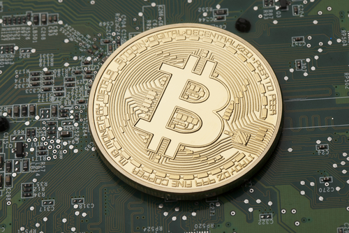 pièce dorée représentant un bitcoin posée sur un circuit électronique