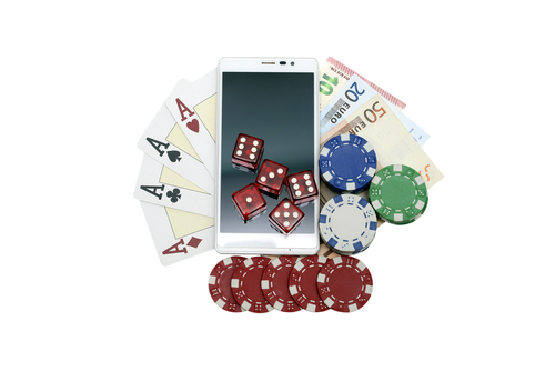 jeu de carte, billet de banque, jetons de casino et plusieurs dés posés sur un smartphone